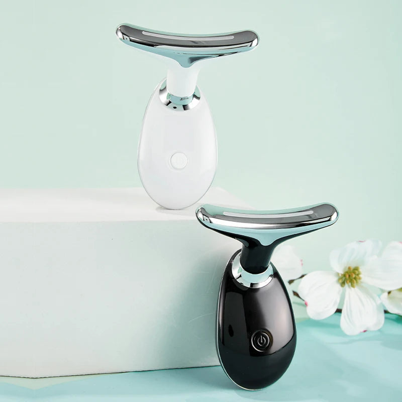 White and black microcurrent face and neck massagers with silver T-shaped heads on light blue background.