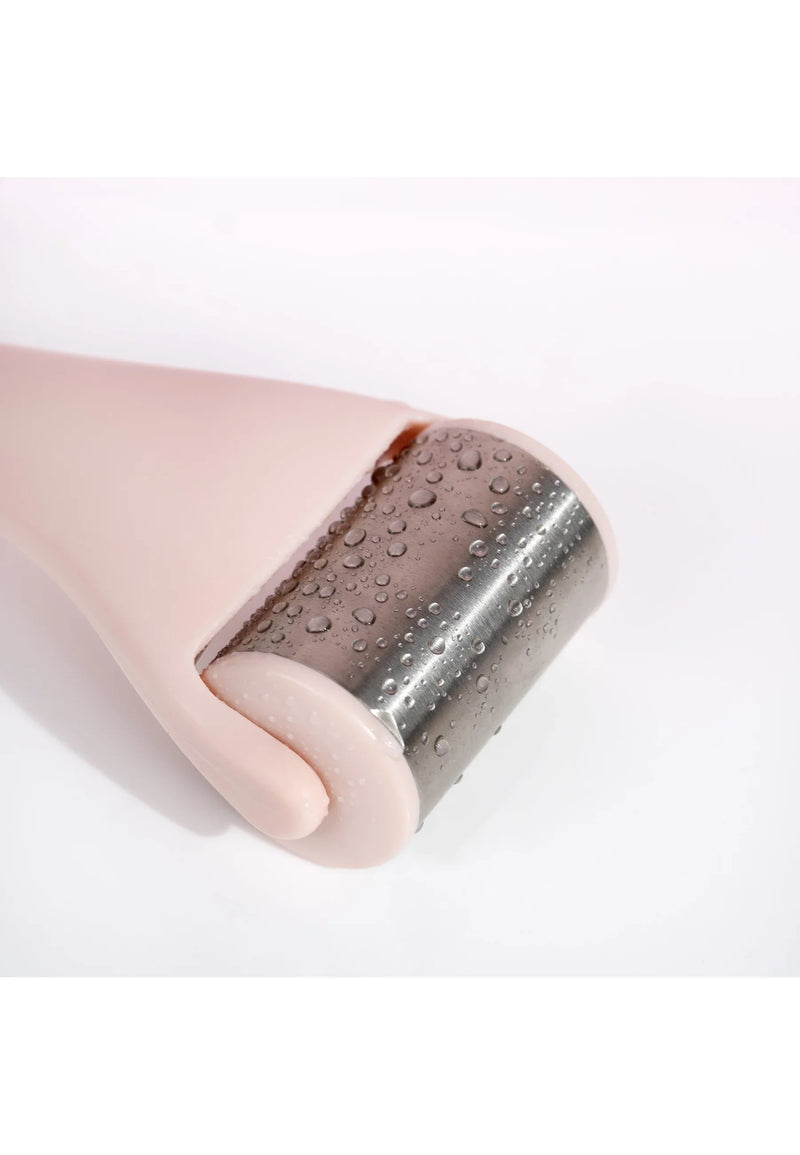 Pink handheld ice roller with textured stainless steel cooling surface and water droplets.